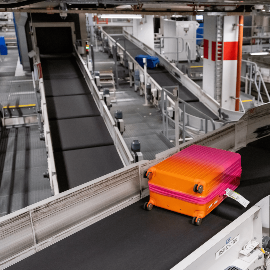 Orange pink suitcase on a baggage conveyor