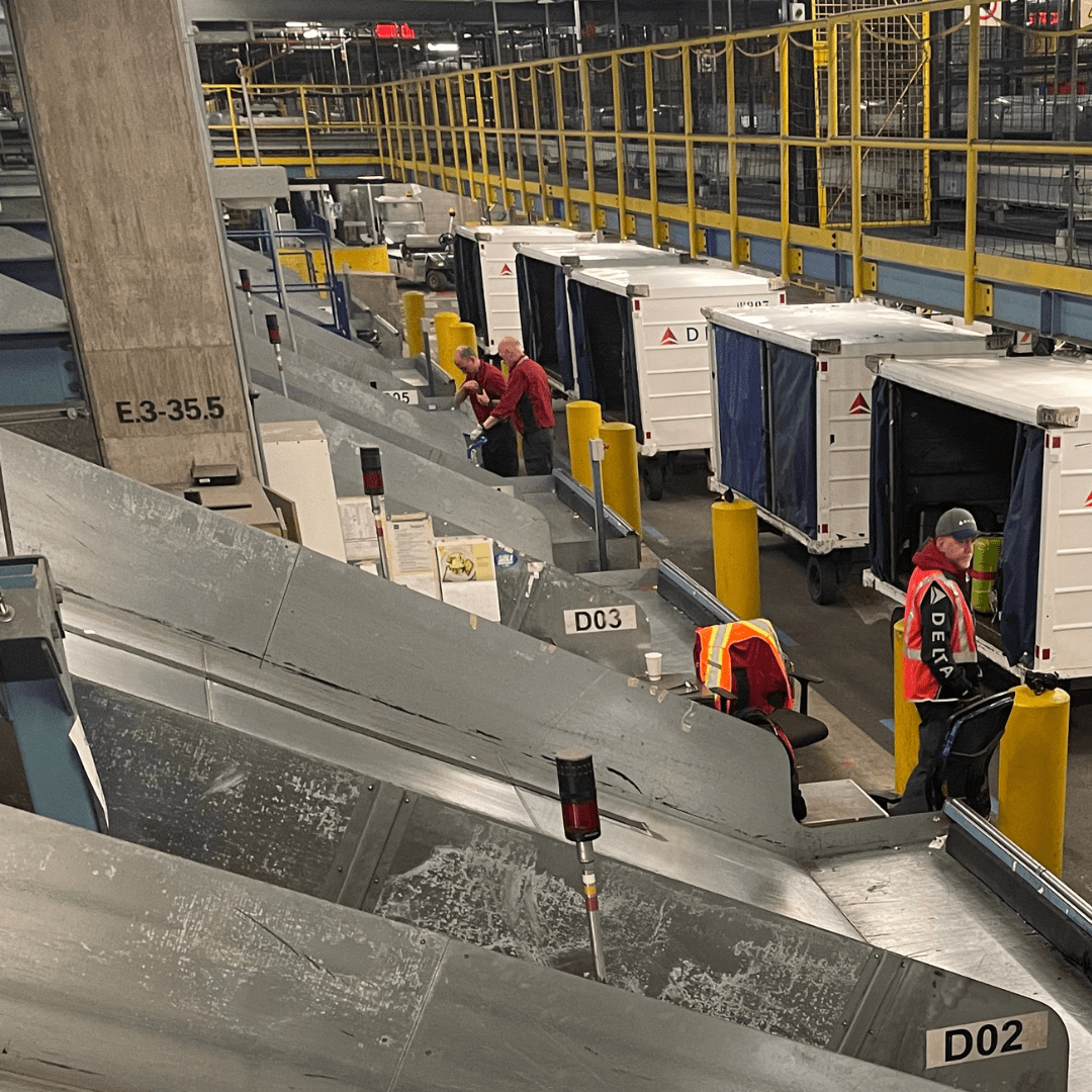 Airport employee loads baggage into transport vehicles