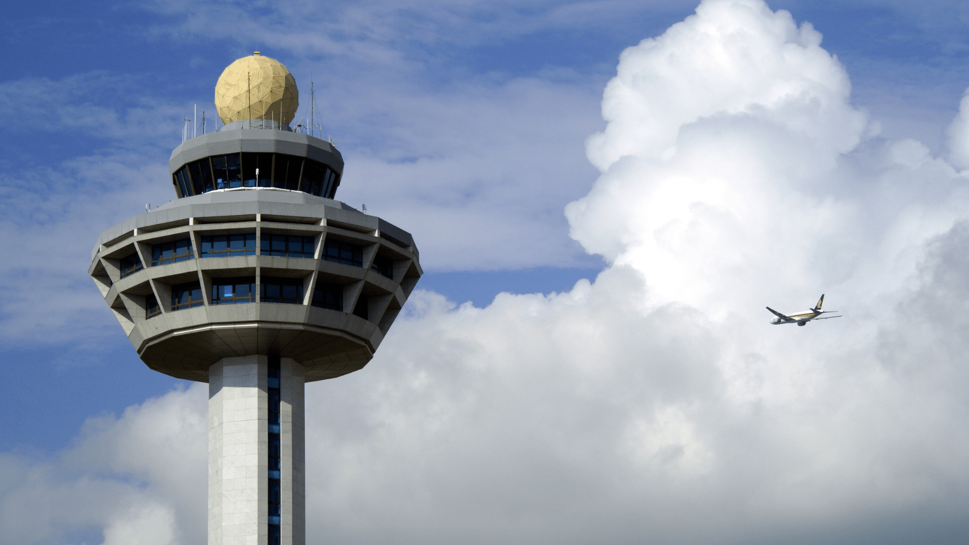 An airplane flies part an airport control tower